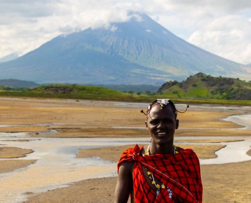 Ein Massai in traditioneller Kleidung im Lake Natron Safari Gebiet mit dem heiligen Berg Ol Doinyo Lengai im Hintergrund