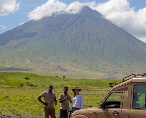 Der Ol Doinyo Lengai (heiliger Berg der Maasai) in der Nähe des Lake Natron mit Safari Gast und Guide im Vordergrund